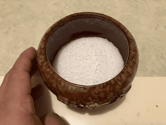 2、接著拍打陶器,讓鹽能平均紮實的分佈在陶器中 (※之後放硬幣會較平穩,倒水時硬幣較不容易東倒西歪)。